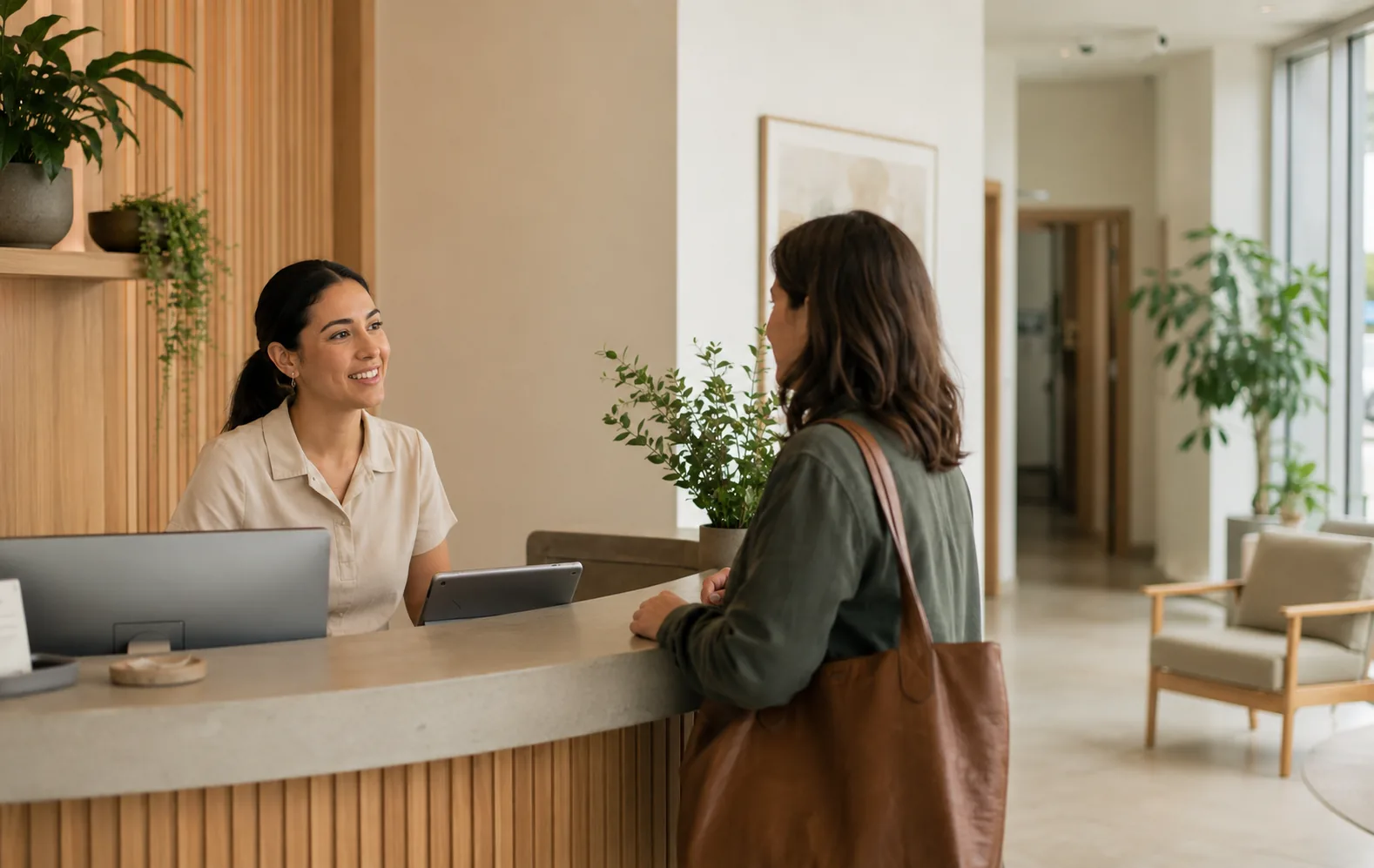 A healthcare practice coordinator speaking with a visitor at reception.